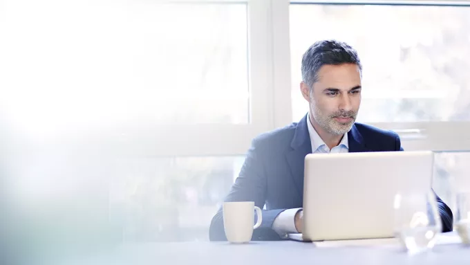 Businessman working on a laptop with a coffee.