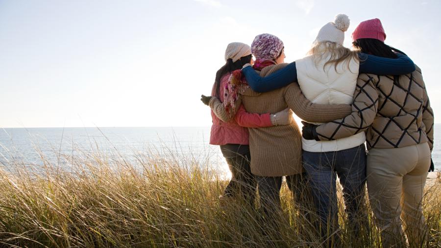 four women in fall clothing hugging