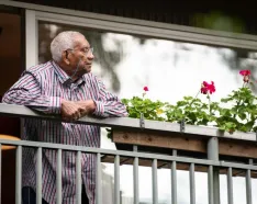 man looking off an apt balcony