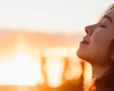 Woman Smiling with her eyes closed in front of a sunset