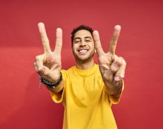 Man holding up peace sign to the camera