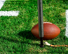 Photo of a football on a field with a pole and chain