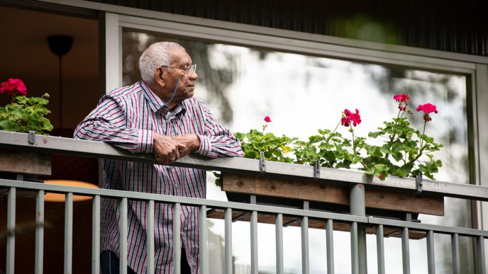 man looking off an apt balcony