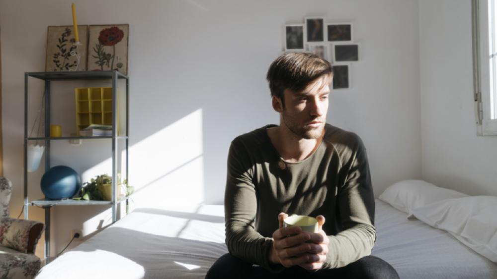 Man sitting on bed in thought