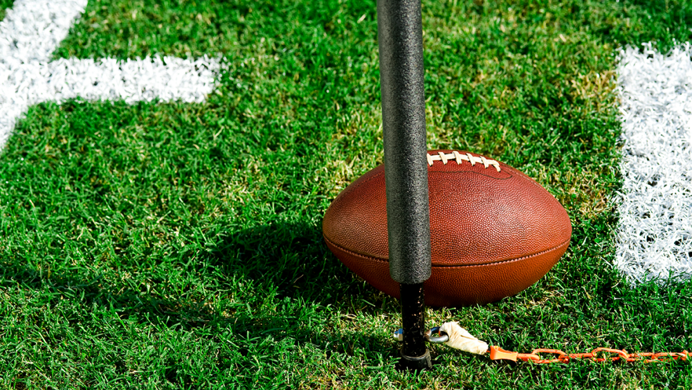 Photo of a football on a field with a pole and chain